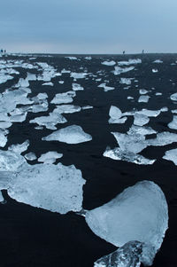 Close-up of snow on sea shore against sky