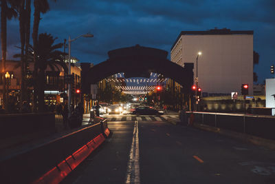 Illuminated road in city against sky at night