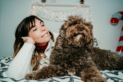 Smiling woman relaxing with dog on bed at home