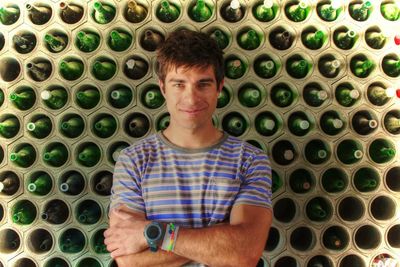 Portrait of young man against bottle installation