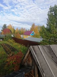 House amidst trees and buildings against sky