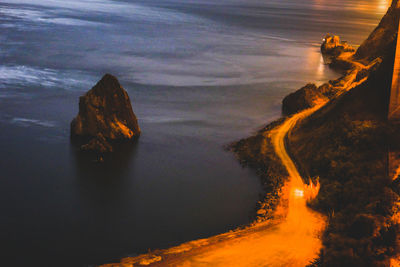 High angle view of rocks at beach against sky during sunset