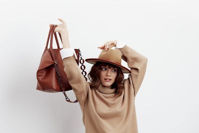 Young woman holding bag against white background