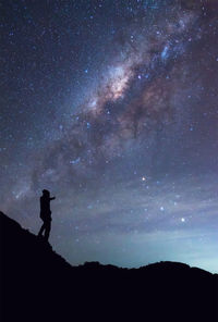 Silhouette mid adult man standing on mountain against star field at night