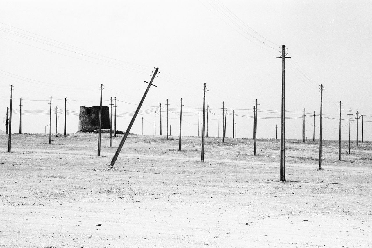 clear sky, sand, beach, fuel and power generation, copy space, alternative energy, tranquility, tranquil scene, environmental conservation, fence, wood - material, day, pole, landscape, nature, wooden post, wind turbine, wind power, sky, outdoors