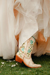 White cowboy boots with floral embroidery with wedding dress.
