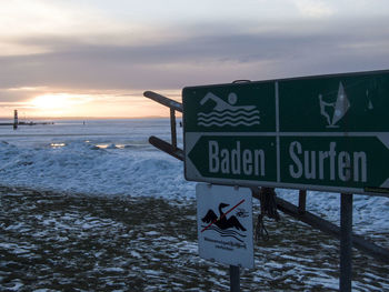 Information sign on sea shore against sky