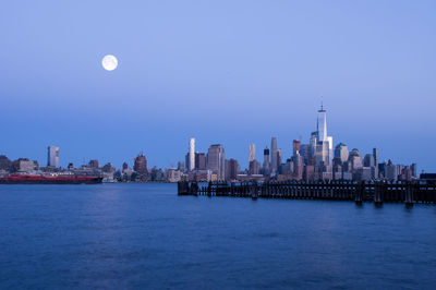 River by city against clear sky at dusk