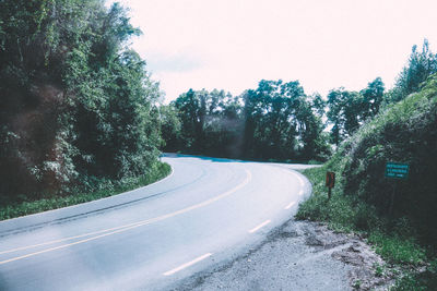 Road amidst trees against clear sky