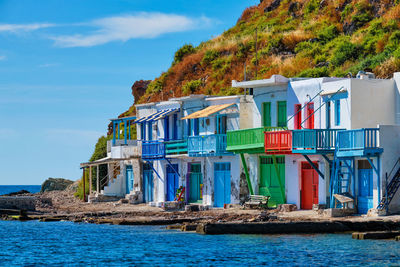 Houses by sea against blue sky