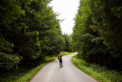Rear view of woman walking on road amidst trees