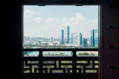 Buildings against sky seen through glass window