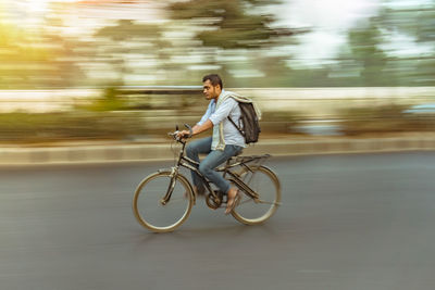 Side view of young man riding bicycle