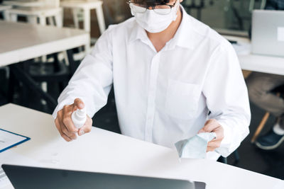 Midsection of man working on white table