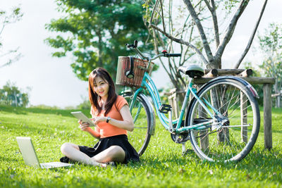 Young woman using smart phone while sitting on grass