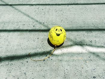 Yellow balloon face on concrete floor