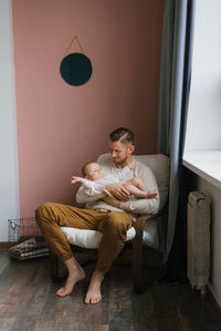 Beautiful family a young dad holds a little son in his arms while sitting in an armchair