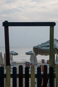 Wooden posts on beach against sky