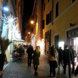 Woman standing on illuminated city street at night