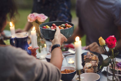 Cropped image of woman serving food to friends at garden party