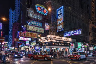 People on city street against illuminated buildings at night