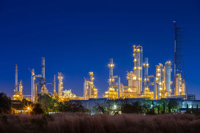 Illuminated factory against blue sky at night