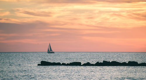 Sailboat in sea against sky during sunset