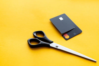 Cut black credit card on yellow background, finance concept