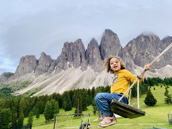 Full length of woman sitting on rock against sky