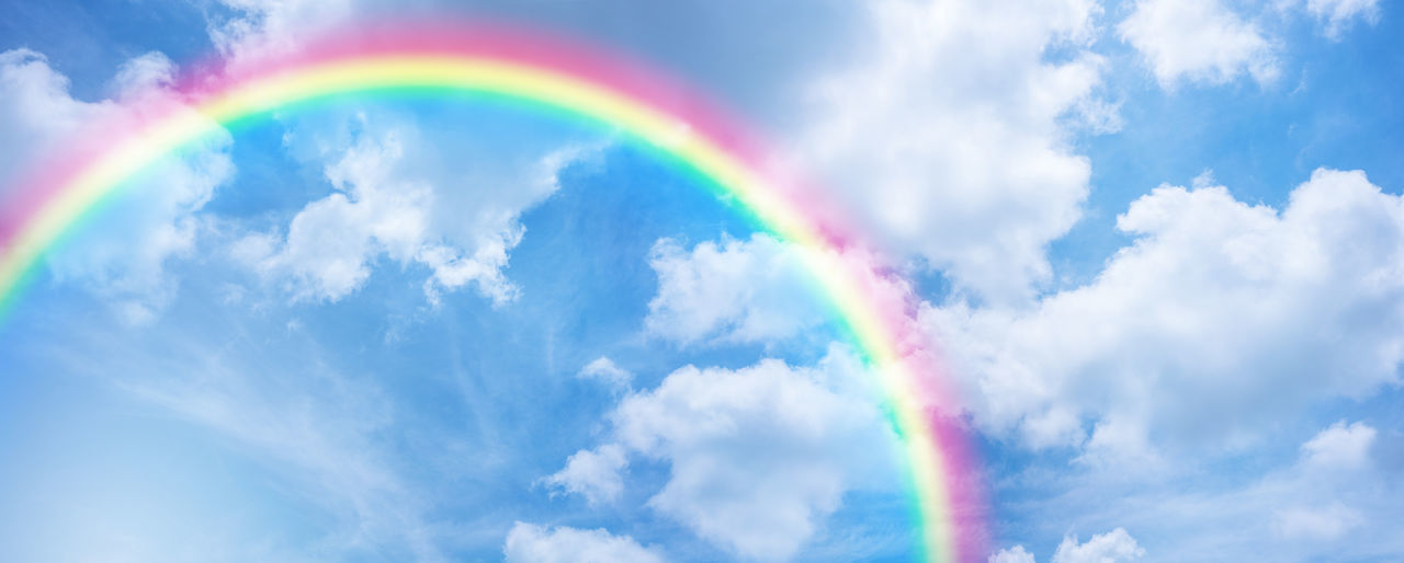 LOW ANGLE VIEW OF RAINBOW AGAINST CLOUDY SKY