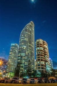 Low angle view of skyscrapers against blue sky at night