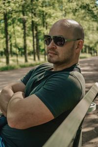 Man wearing sunglasses while sitting on bench at park