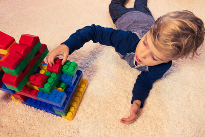 Boy playing with colorful toy blocks at home