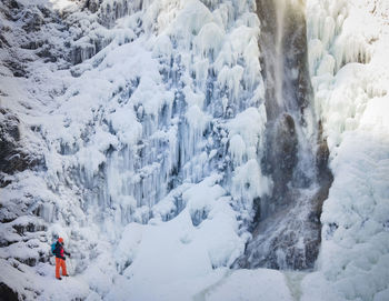 High angle view of man on snow covered mountains by waterfall during winter