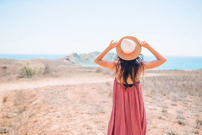 Woman wearing hat standing on land against sky