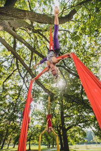 Low angle view of young woman doing acrobatic activity with fabric