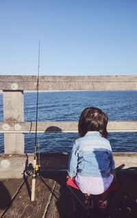 Rear view of girl looking at sea against clear sky