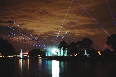 Illuminated bridge over river against sky in city at night