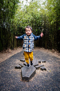 Portrait of boy standing on footpath