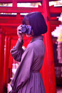 Woman photographing while standing outdoors