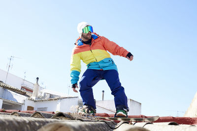 Man on a rooftop enjoying the sun and snowboarding