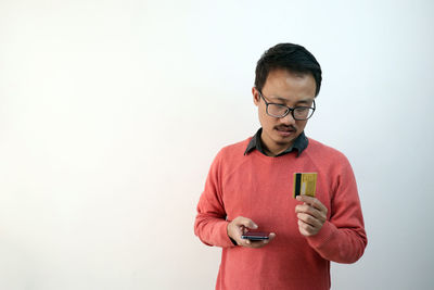 Mid adult man standing against wall against white background