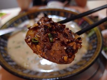 Close-up of slice of spicy beef on chopsticks