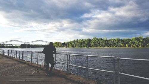 Man standing on bridge over river against sky