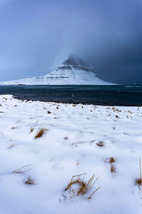 Scenic view of snow covered kirkjufell during a winter storm with snowflakes falling