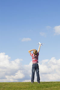 Full length of boy standing on field against sky