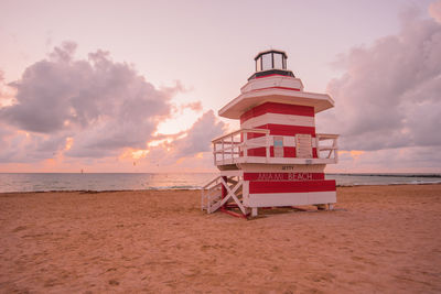 Lifeguard hut on beach against sky during sunset