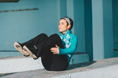 Smiling young woman sitting against wall