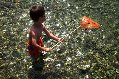 High angle view of shirtless boy fishing in sea