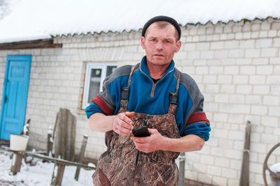 Russian young man standing outside on winter countryside background. construction worker holding